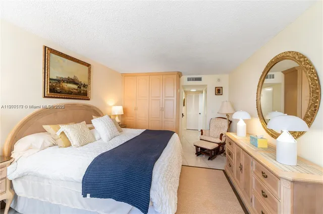 a spacious bedroom with a bed a mirror on the dresser and a window