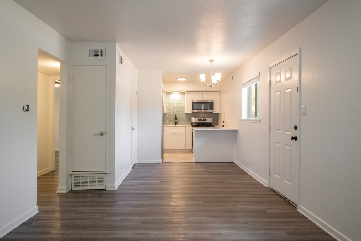 806 East 13th Street, Unit 105 Georgetown, TX 78626 - Photo 15 of 25 Kitchen with white cabinetry, backsplash, a peninsula, light countertops, and dark wood finished floors