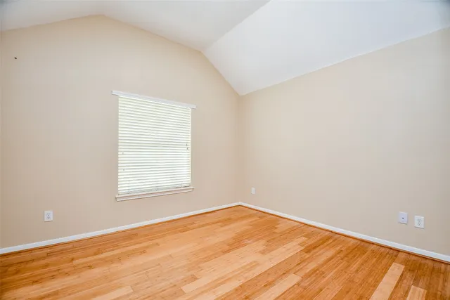 an empty room with wooden floor and a window