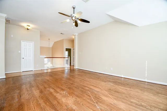 an empty room with wooden floor fan and windows