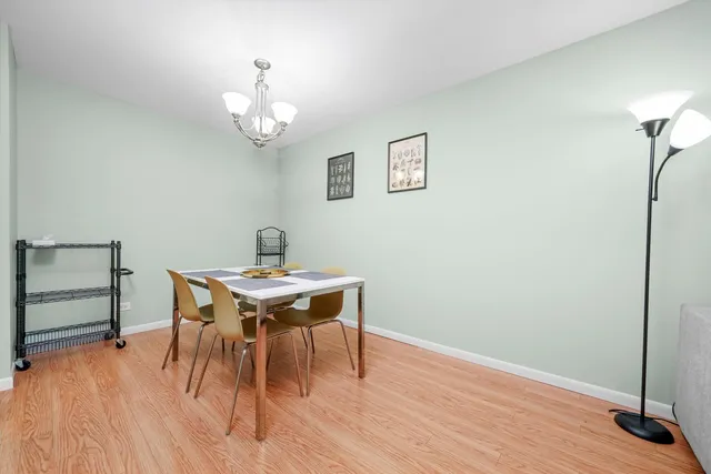 a dining room with wooden floor a chandelier a wooden table and chairs