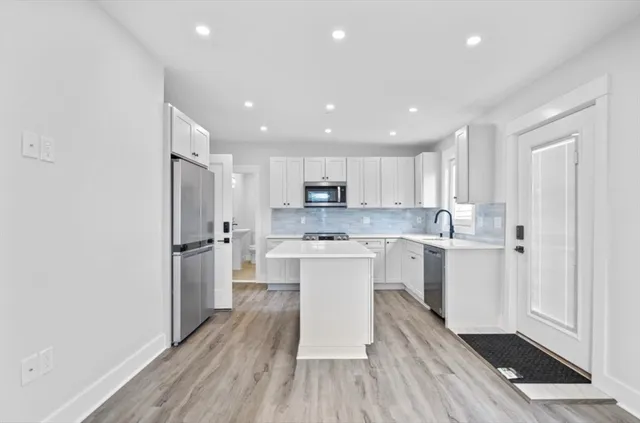 a kitchen with white cabinets and stainless steel appliances