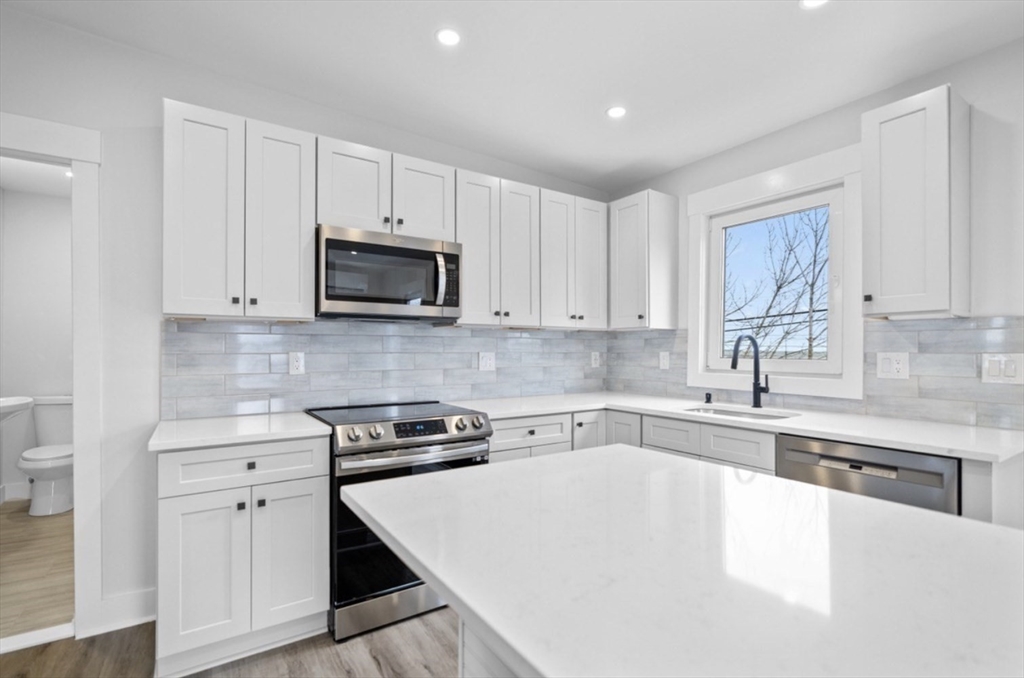 6 Garfield Avenue, Unit 1 Revere, MA 02151 - Photo 4 of 9 a kitchen with granite countertop a stove a sink and a microwave