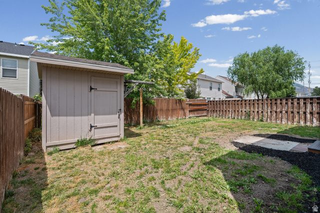 1346 Archmore Drive Springville, UT 84663 - Photo 27 of 32 Expansive backyard featuring a storage shed, wooden perimeter fencing, and a paved patio area