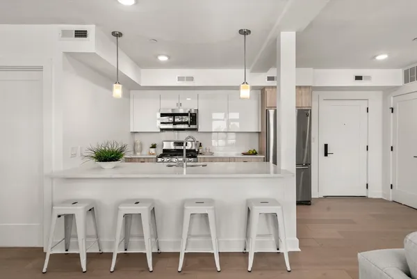 a kitchen with stainless steel appliances kitchen island granite countertop a refrigerator and white cabinets