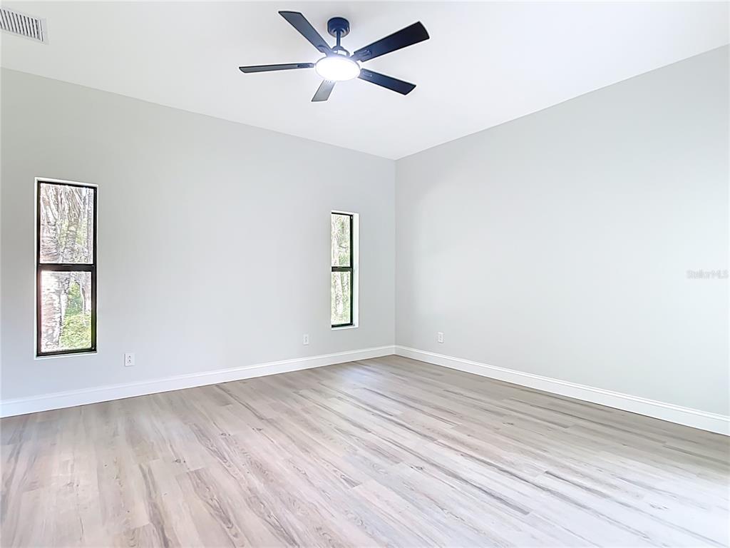 6231 Rowe Street Englewood, FL 34224 - Photo 16 of 35 an empty room with wooden floor ceiling fan and windows