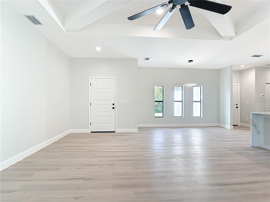 6231 Rowe Street Englewood, FL 34224 - Photo 2 of 35 an empty room with wooden floor ceiling fan and windows