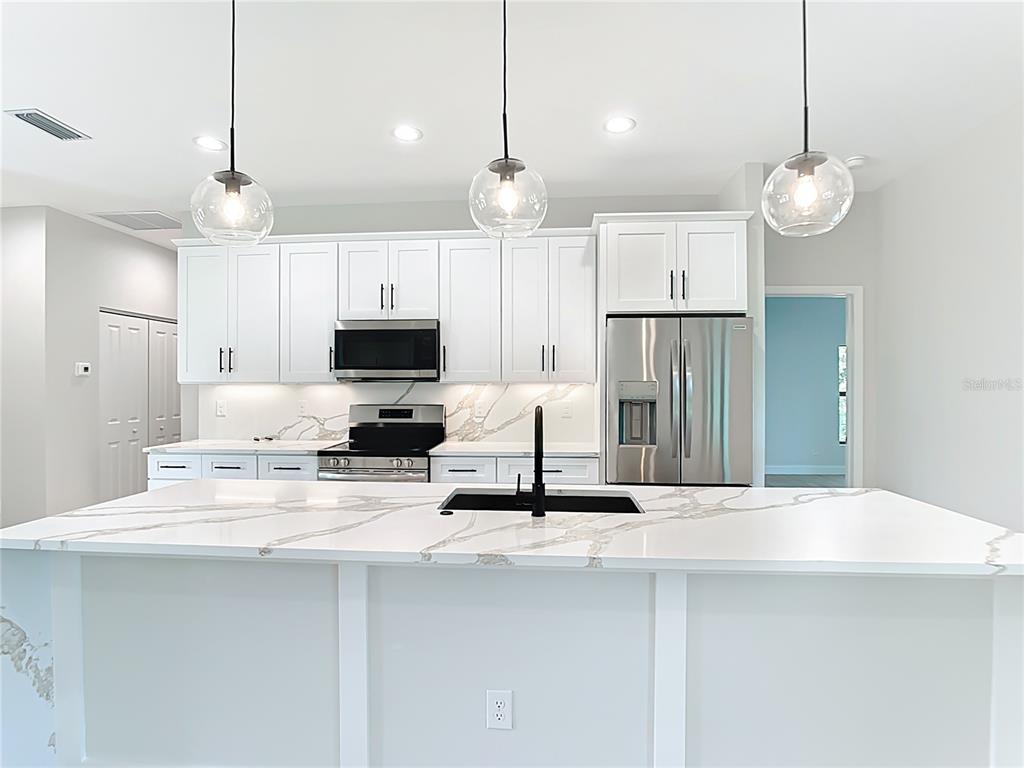 6231 Rowe Street Englewood, FL 34224 - Photo 9 of 35 a large kitchen with kitchen island a sink stainless steel appliances and cabinets