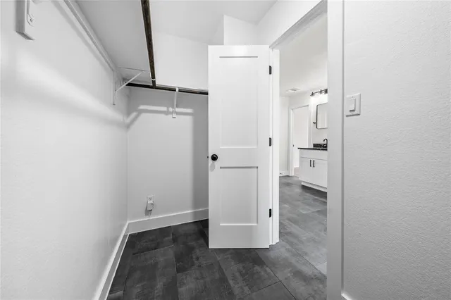 a view of an empty room with wooden floor and a ceiling fan