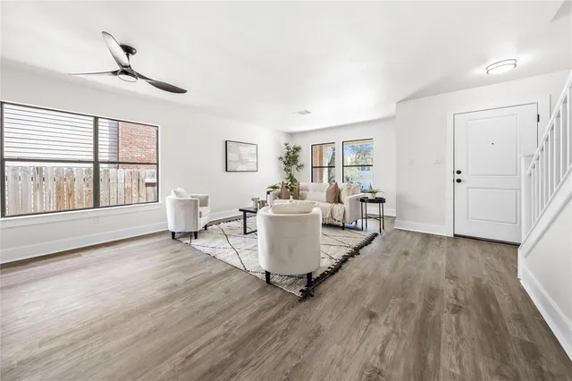 a living room with couches a coffee table and a potted plant with wooden floor