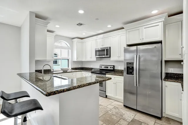a kitchen with granite countertop white cabinets and appliances