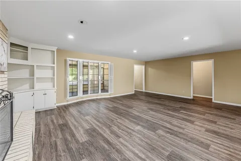 a view of an empty room with wooden floor and windows