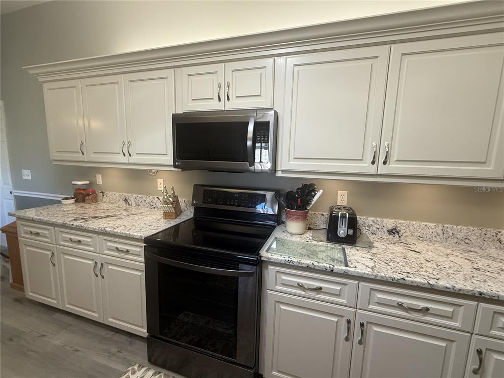 11263 Southwest 138th Lane Dunnellon, FL 34432 - Photo 3 of 25 a kitchen with granite countertop white cabinets and a stove top oven