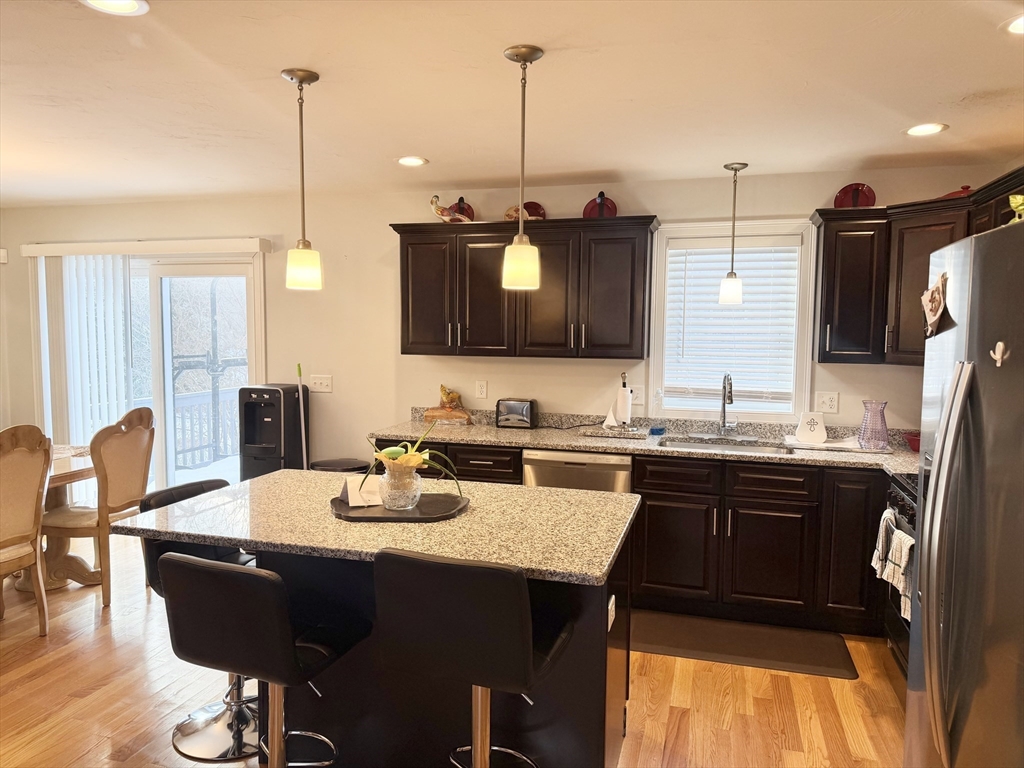 60 A Danforth Street, Unit A Taunton, MA 02780 - Photo 2 of 10 a kitchen with stainless steel appliances granite countertop a sink a stove a refrigerator a dining table and chairs with wooden floor