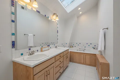 a bathroom with a sink double vanity granite tub and a mirror