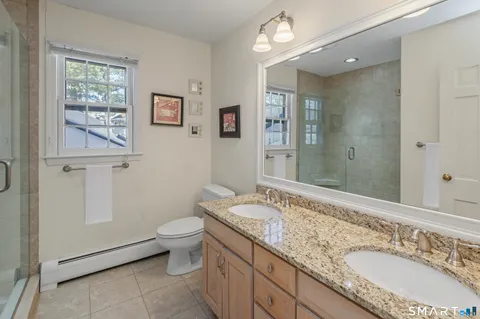 a bathroom with a granite countertop double vanity sink a mirror and a toilet