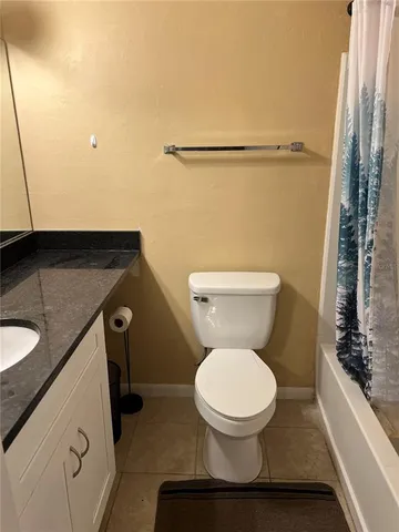 a bathroom with a granite countertop toilet sink and mirror