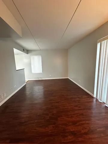 an empty room with wooden floor and windows with curtains