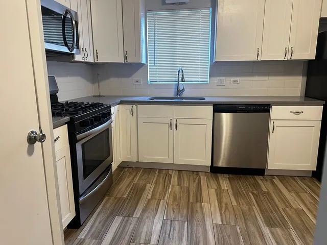 a kitchen with granite countertop a sink cabinets stainless steel appliances and a counter space
