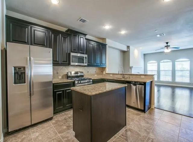 a kitchen with stainless steel appliances granite countertop a stove a refrigerator and a sink