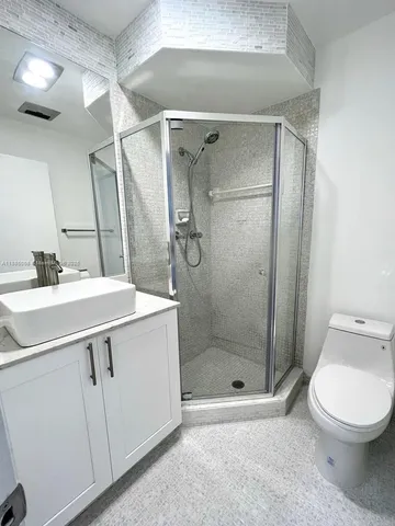 a bathroom with a shower sink vanity and toilet