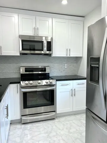 a kitchen with stainless steel appliances white cabinets and a stove top oven