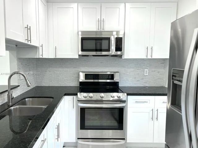 a kitchen with stainless steel appliances a stove a sink a microwave and cabinets