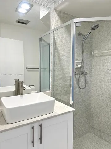 a bathroom with a sink shower and a mirror