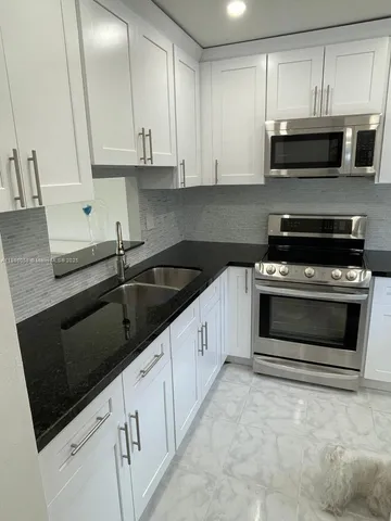 a kitchen with granite countertop white cabinets and black appliances
