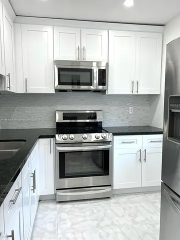a kitchen with granite countertop a stove microwave and sink