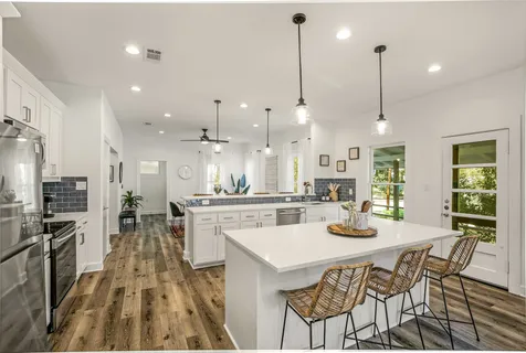 a kitchen with stainless steel appliances kitchen island granite countertop a stove a sink a oven a dining table and chairs