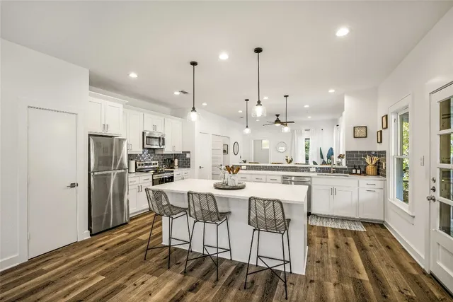 a kitchen with stainless steel appliances kitchen island granite countertop a refrigerator and a stove top oven