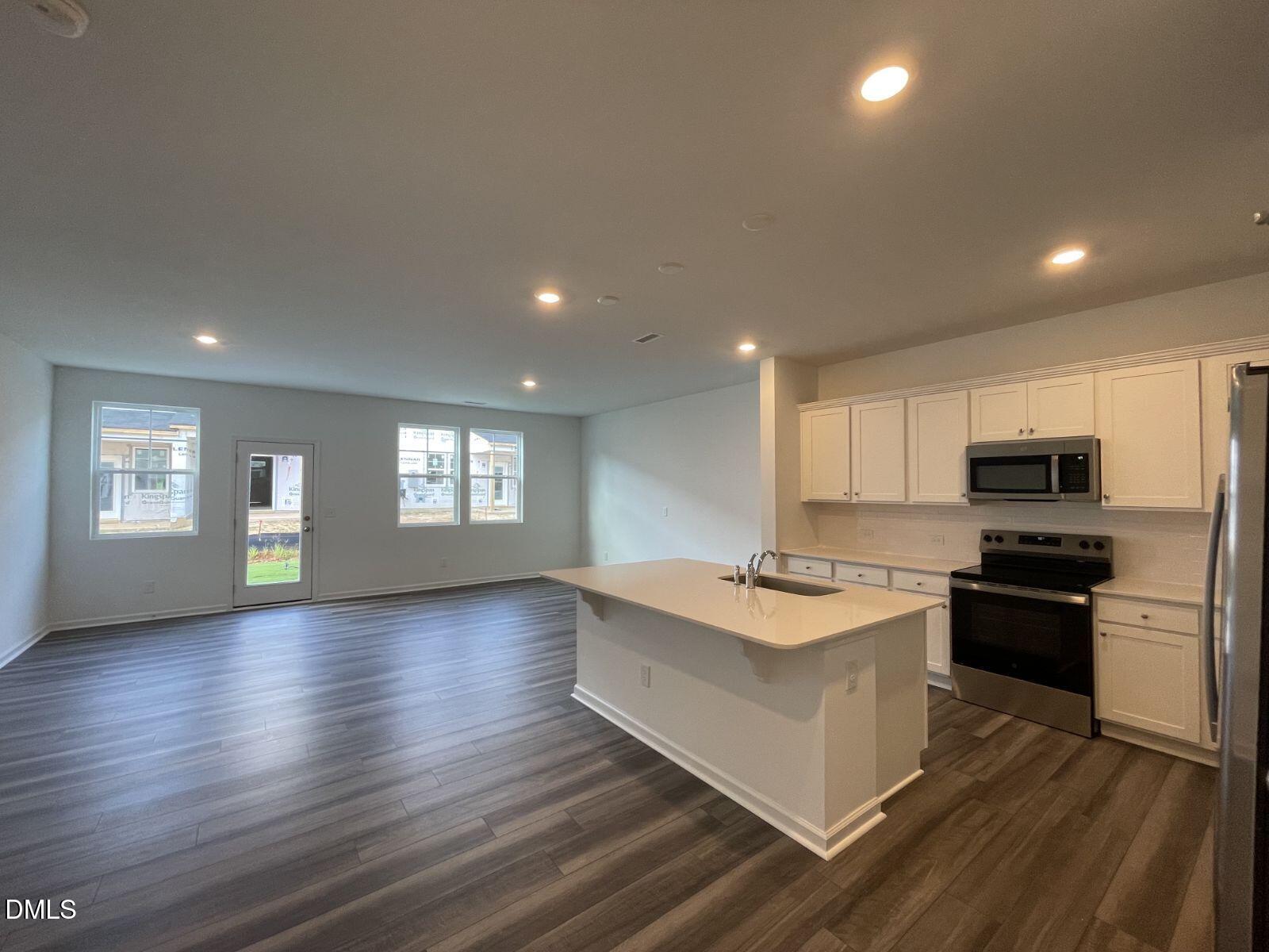 213 Lily Patch Lane Smithfield, NC 27577 - Photo 5 of 13 a kitchen with stainless steel appliances granite countertop a stove top oven a sink dishwasher and a refrigerator with wooden floor