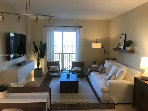 a living room with furniture a flat screen tv and a window