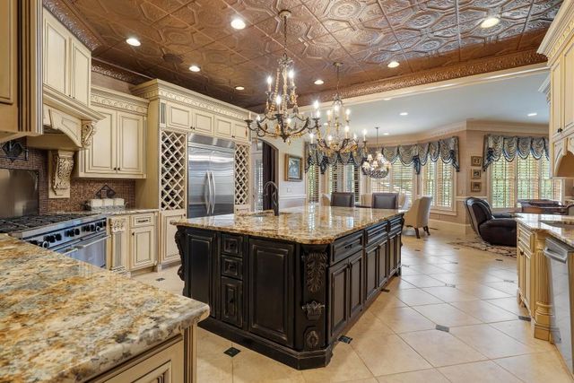 a kitchen with stainless steel appliances granite countertop a sink a stove a dining table and chairs