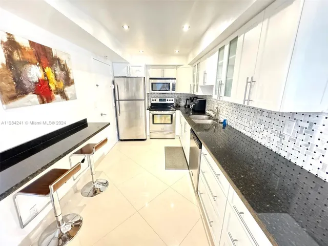 a kitchen with stainless steel appliances granite countertop a sink and a refrigerator