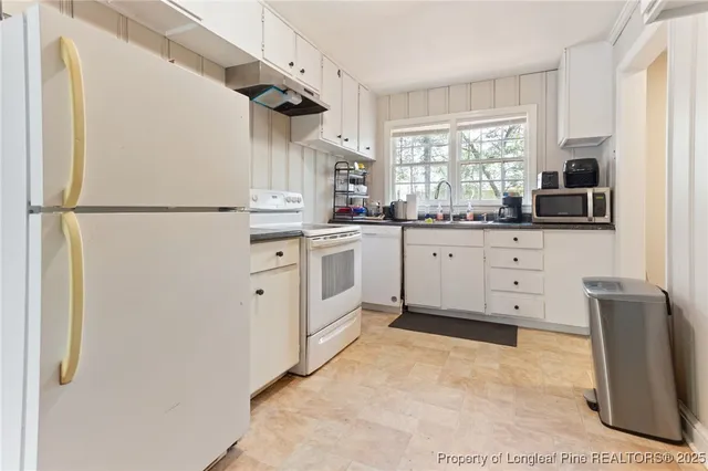 a kitchen with granite countertop cabinets appliances a sink and a window