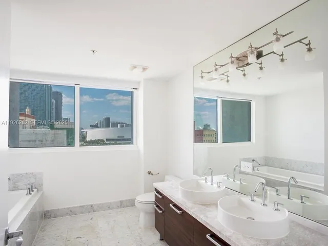 a bathroom with a bathtub shower sink vanity and toilet