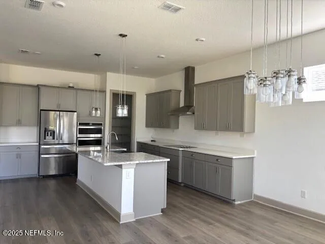 a large kitchen with granite countertop a large counter top space stainless steel appliances and a chandelier