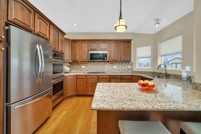 a kitchen with stainless steel appliances granite countertop a refrigerator a stove and a sink with granite countertops