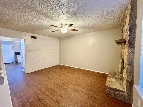 an empty room with wooden floor and ceiling fan