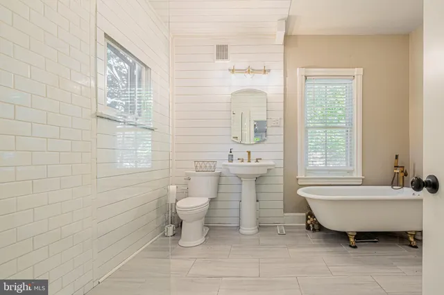 a bathroom with a sink toilet a mirror and bathtub