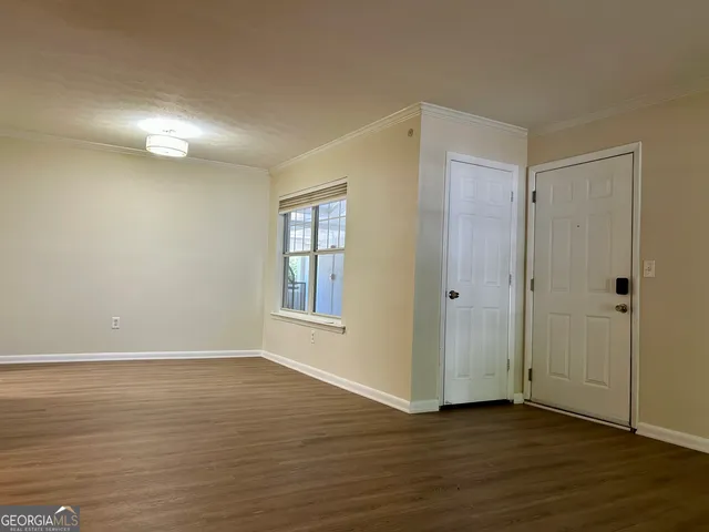 a view of an empty room with wooden floor and closet