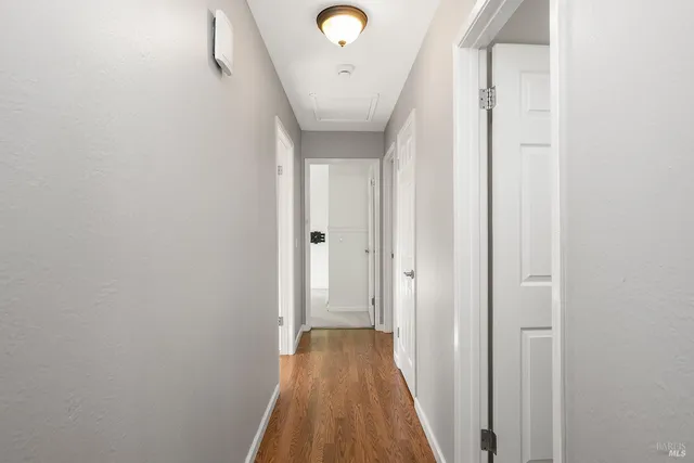 a view of a hallway with wooden floor and a bathroom
