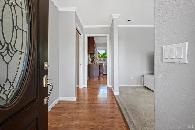 a view of a hallway with wooden floor and a living room
