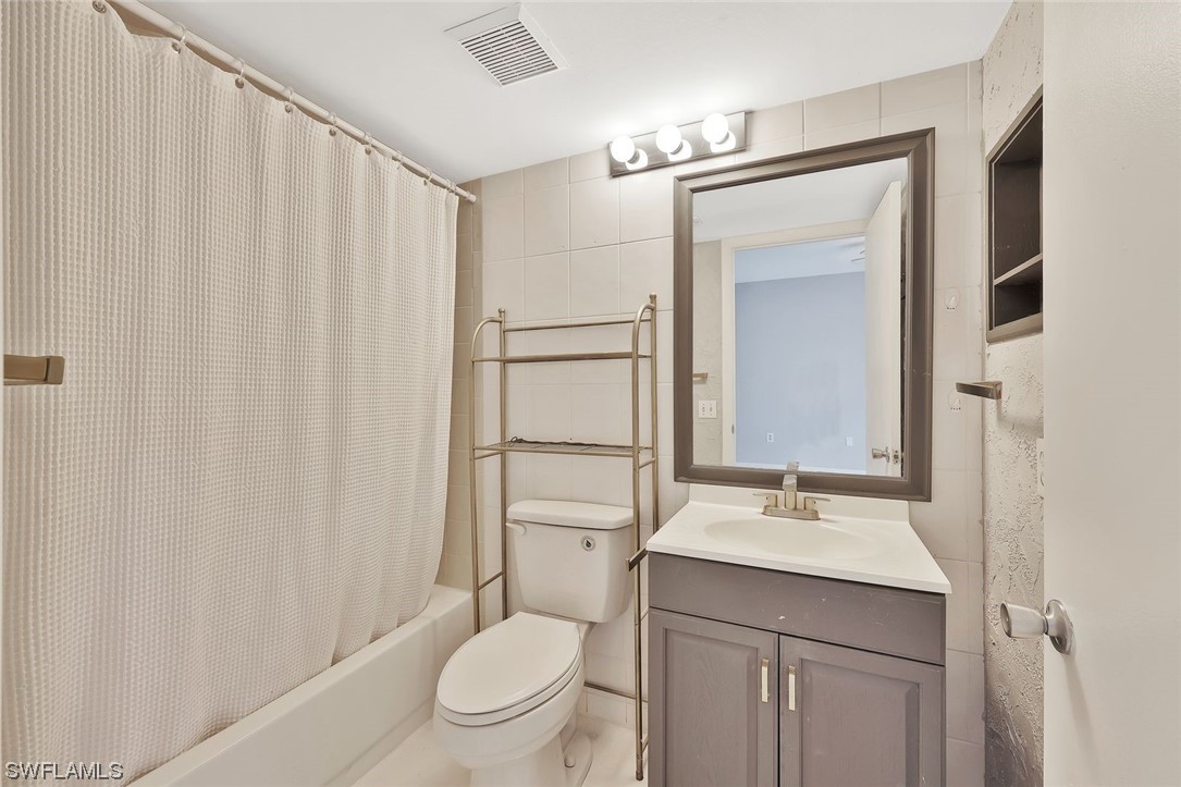 13373 Broadhurst Loop Fort Myers, FL 33919 - Photo 15 of 25 a bathroom with a sink a toilet a mirror and shower curtain