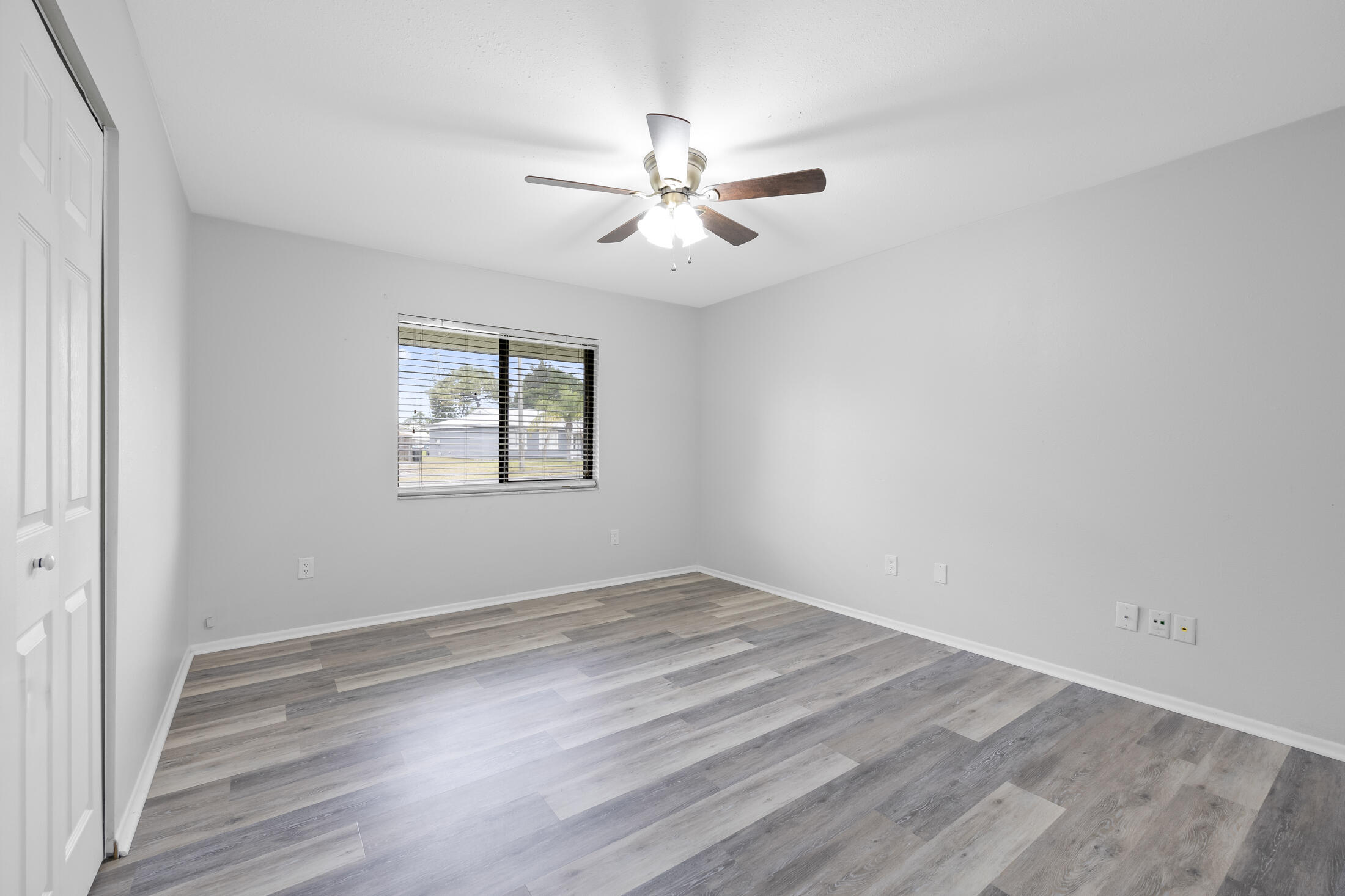 1180 Mascot Street Northeast Palm Bay, FL 32905 - Photo 17 of 24 an empty room with wooden floor ceiling fan and windows