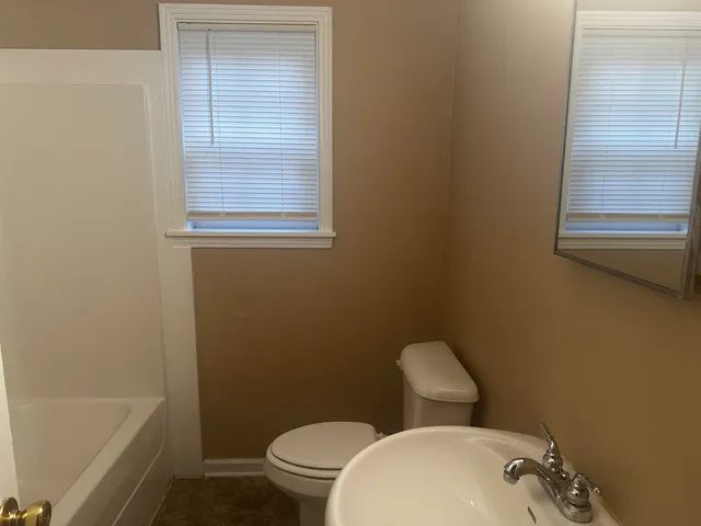 a white toilet sitting next to a bath tub
