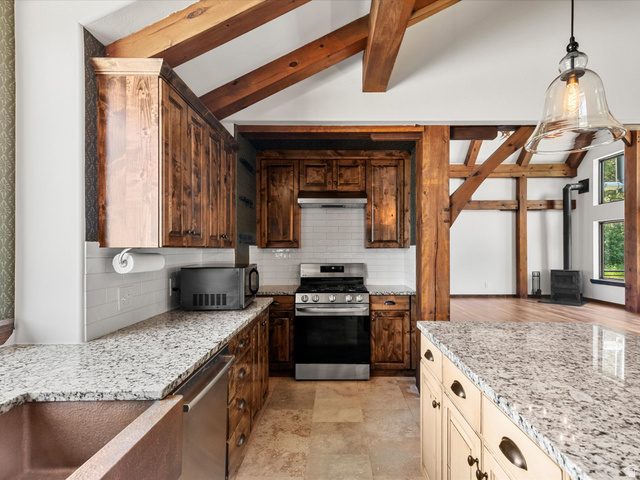 1225 Old Oregon Road Soda Springs, ID 83276 - Photo 12 of 67 Kitchen featuring wood cabinetry, light-toned granite countertops, a copper-toned farmhouse sink, and stainless steel appliances