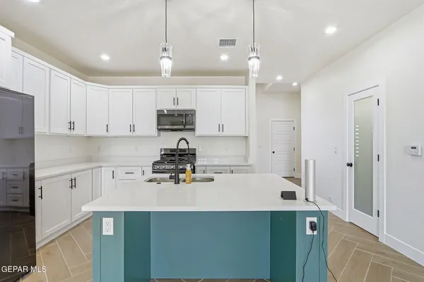 a kitchen with a sink a stove a refrigerator and white cabinets